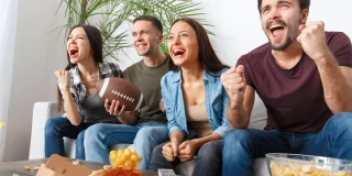 Group of friends hosting a football watching party on TV.