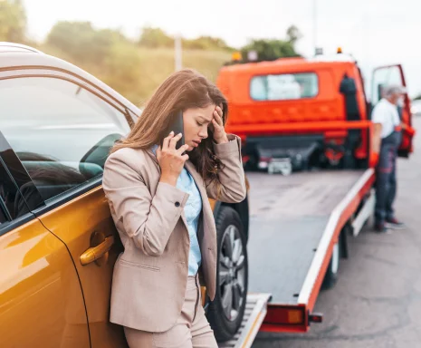 woman calling someone while roadside assistance is helping her on the road