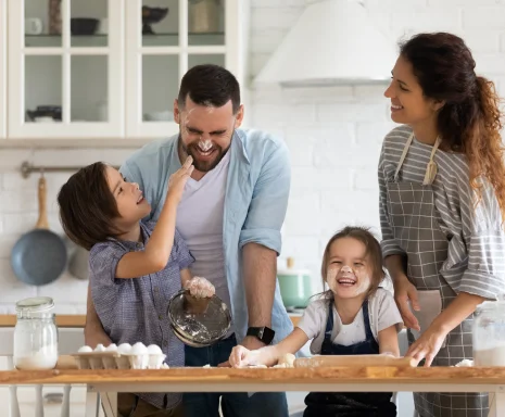 happy smiling parents enjoy weekend play with small children doing bakery cooking in kitchen