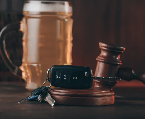 Glass of beer, car keys and judge gavel on a wooden table. Alcohol and car accidents, cheap DUI insurance.