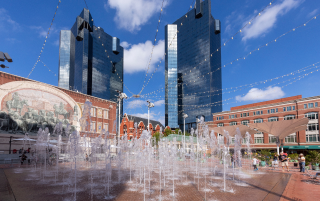 Visitors relax by the fountains at Sundance Square Plaza in Fort Worth on Main Street, with a mural depicting the iconic longhorns of the Stockyards – Fort Worth, cheap car insurance in Texas