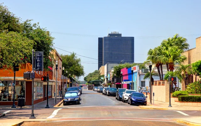 Main Street in McAllen, the largest city in Hidalgo County, Texas, features various establishments, buildings, and parked cars – McAllen, cheap car insurance in Texas