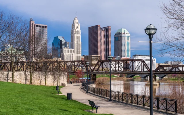 Columbus, Ohio skyline of the downtown financial district seen from the Scioto River through a railroad truss bridge – Columbus, cheap car insurance in Ohio